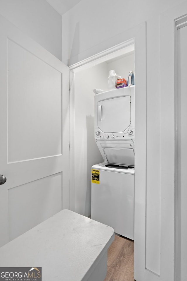 laundry room with laundry area, stacked washing maching and dryer, and wood finished floors