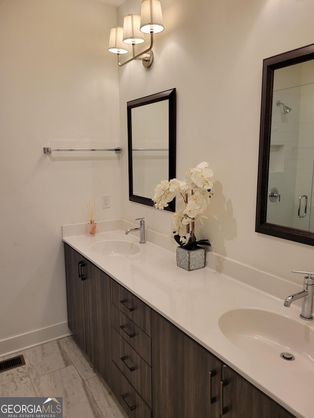 bathroom featuring double vanity, visible vents, a sink, and a shower with shower door