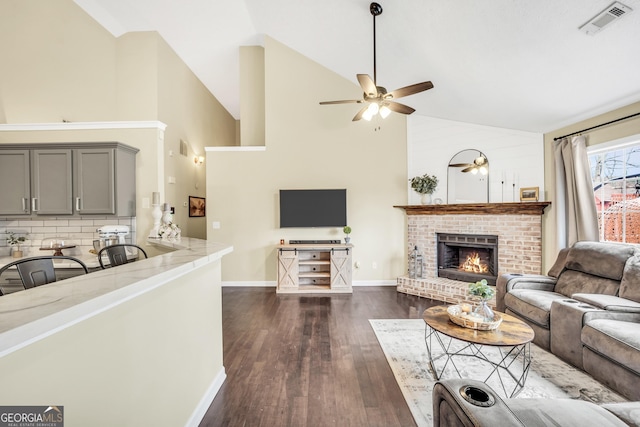 living room with ceiling fan, high vaulted ceiling, a fireplace, and dark hardwood / wood-style flooring