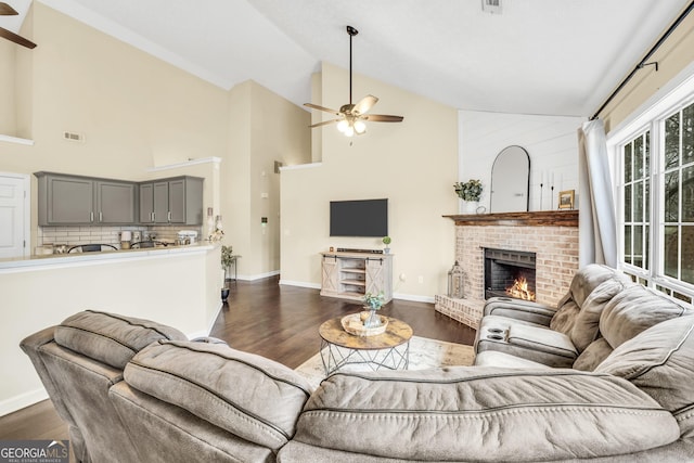 living room featuring dark hardwood / wood-style flooring, high vaulted ceiling, a fireplace, and ceiling fan