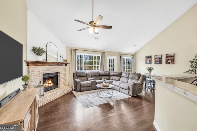 living room with ceiling fan, a brick fireplace, dark wood-type flooring, and high vaulted ceiling