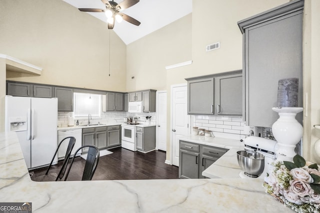 kitchen featuring gray cabinets, sink, light stone counters, and white appliances