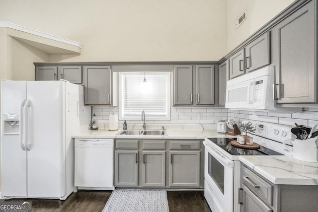 kitchen with light stone counters, white appliances, gray cabinets, and sink