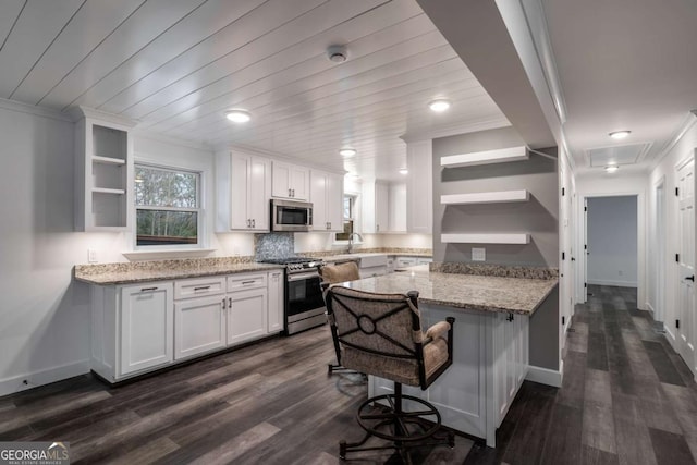 kitchen with stainless steel appliances, light stone countertops, a breakfast bar area, and white cabinets