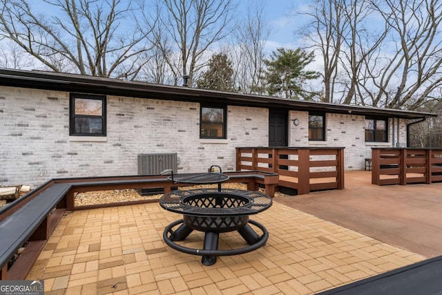 rear view of property with a fire pit, central AC, and a patio