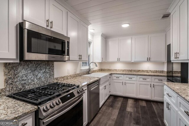 kitchen featuring appliances with stainless steel finishes, light stone countertops, sink, and white cabinets