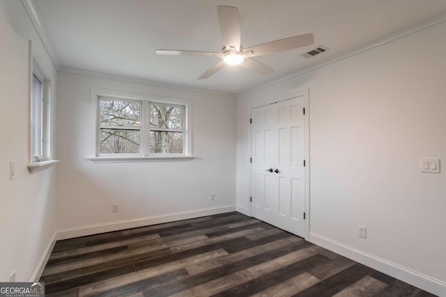 unfurnished bedroom with a closet, crown molding, dark hardwood / wood-style floors, and ceiling fan