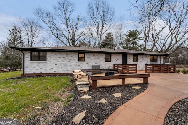 rear view of house with a wooden deck, a fire pit, cooling unit, and a lawn