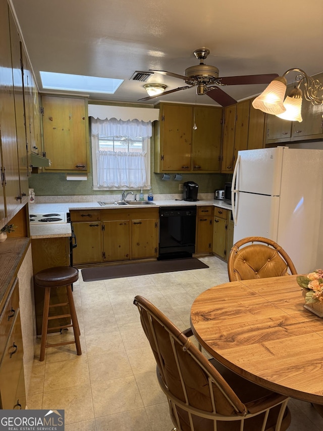 kitchen with sink, light tile patterned floors, a skylight, black dishwasher, and white refrigerator