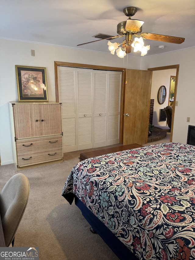 bedroom with crown molding, light colored carpet, ceiling fan, and a closet