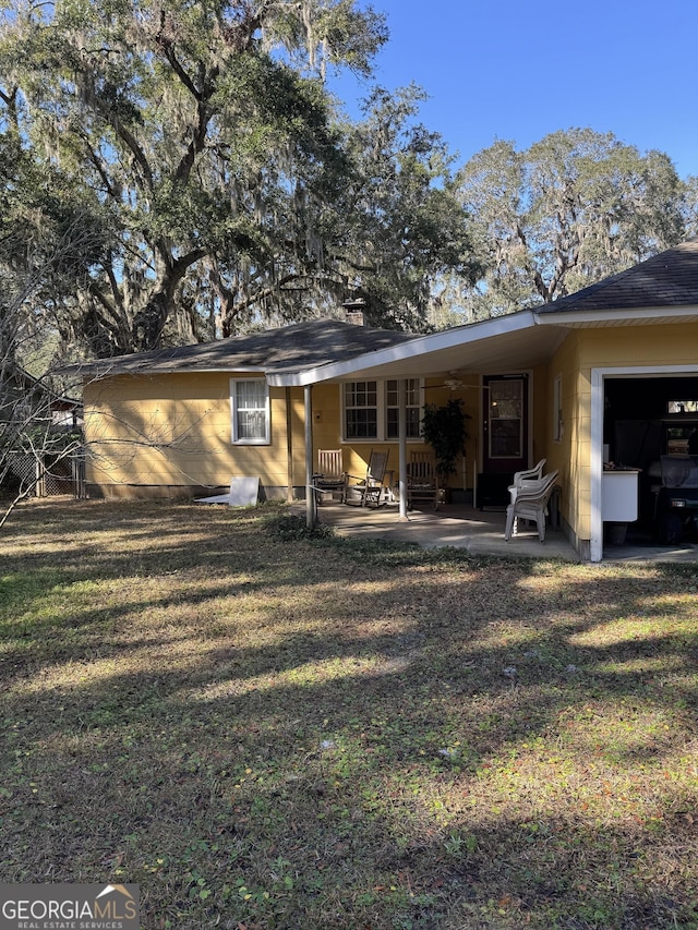 rear view of house with a garage, a patio area, and a lawn