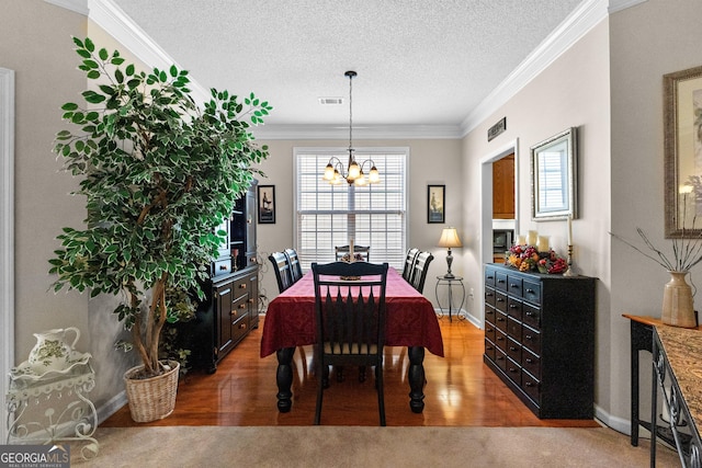 dining room with an inviting chandelier, hardwood / wood-style floors, ornamental molding, and a textured ceiling