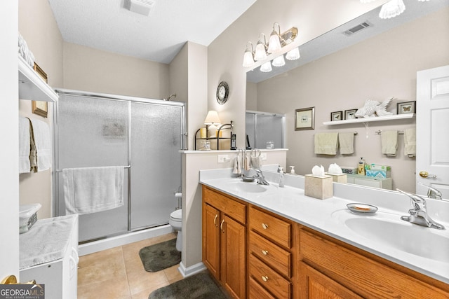 bathroom featuring a shower with door, vanity, tile patterned floors, and toilet