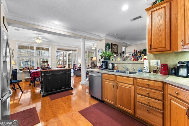 kitchen with ornate columns, appliances with stainless steel finishes, sink, ceiling fan, and light hardwood / wood-style floors