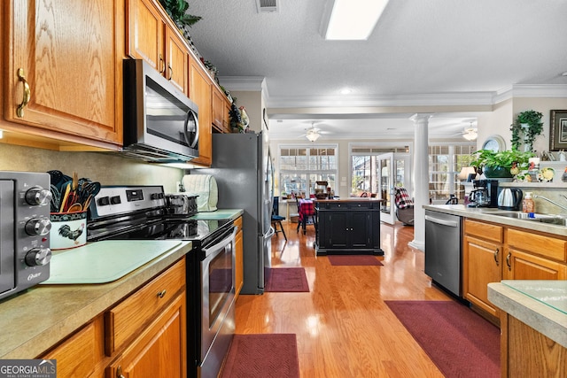 kitchen featuring sink, ornate columns, crown molding, ceiling fan, and stainless steel appliances