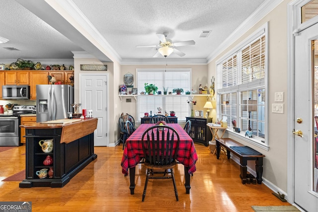 dining room with ceiling fan, ornamental molding, a textured ceiling, and light wood-type flooring