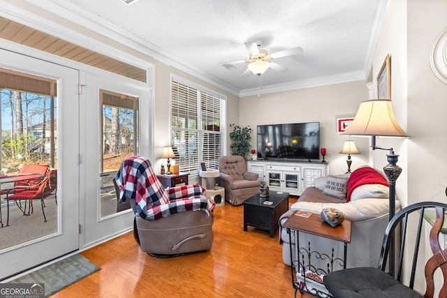 living room featuring crown molding, wood-type flooring, a wealth of natural light, and ceiling fan