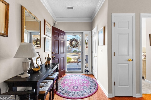 entrance foyer with wood-type flooring, a textured ceiling, and crown molding