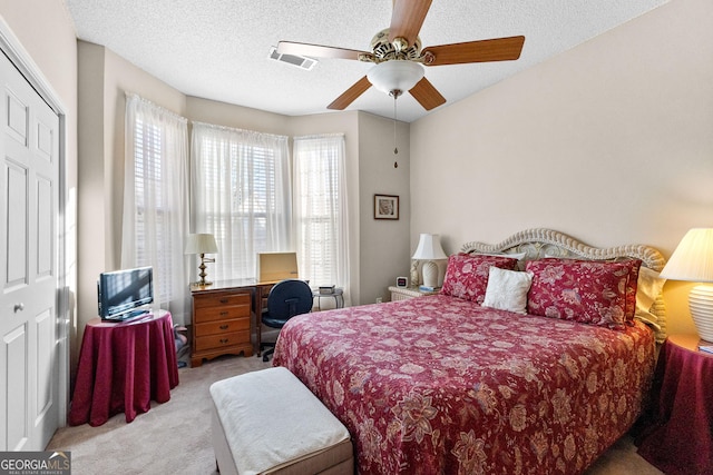 carpeted bedroom featuring ceiling fan and a textured ceiling