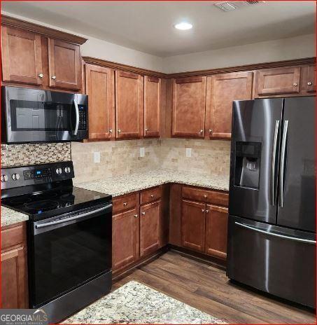 kitchen featuring light stone countertops, backsplash, stainless steel appliances, and dark hardwood / wood-style floors