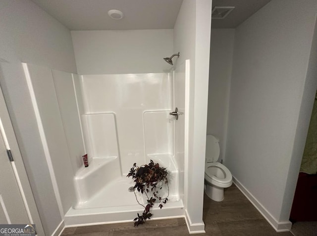 bathroom with a shower, hardwood / wood-style floors, and toilet