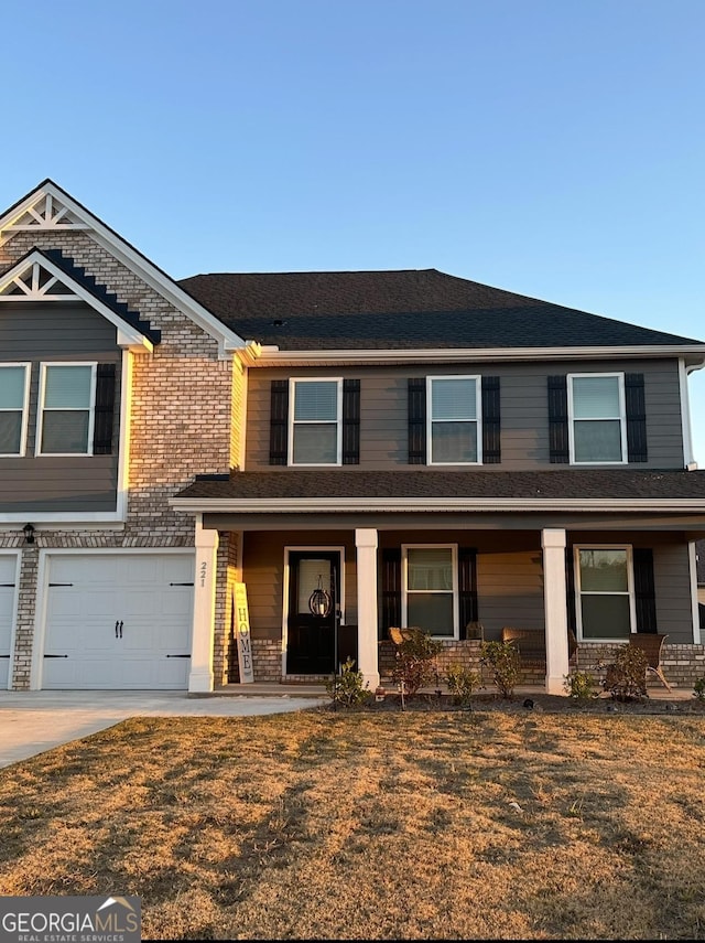 view of front of property featuring a garage, a front yard, and a porch