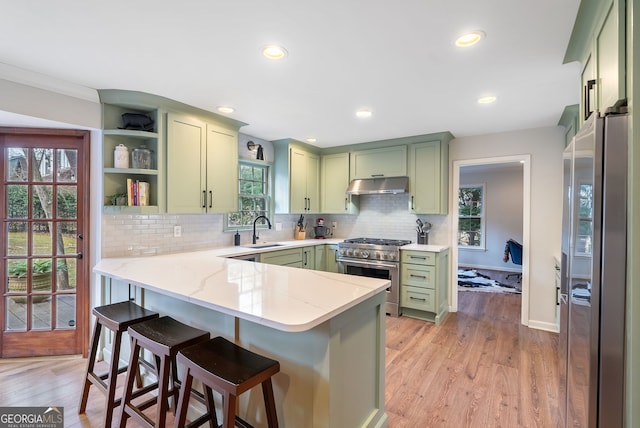 kitchen featuring green cabinetry, sink, kitchen peninsula, stainless steel appliances, and light stone countertops