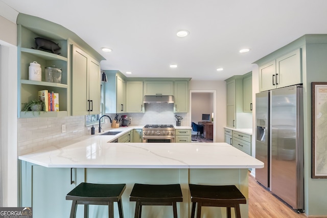 kitchen featuring light stone counters, sink, stainless steel appliances, and green cabinetry