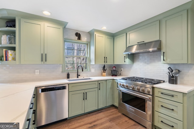 kitchen featuring sink, green cabinets, hardwood / wood-style flooring, stainless steel appliances, and light stone countertops