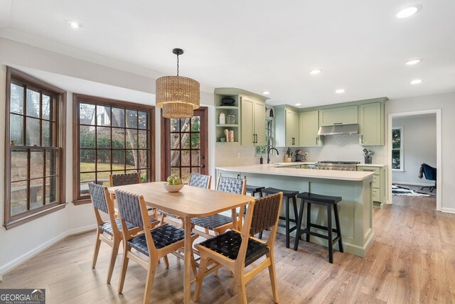 dining room featuring crown molding, sink, an inviting chandelier, and light hardwood / wood-style floors