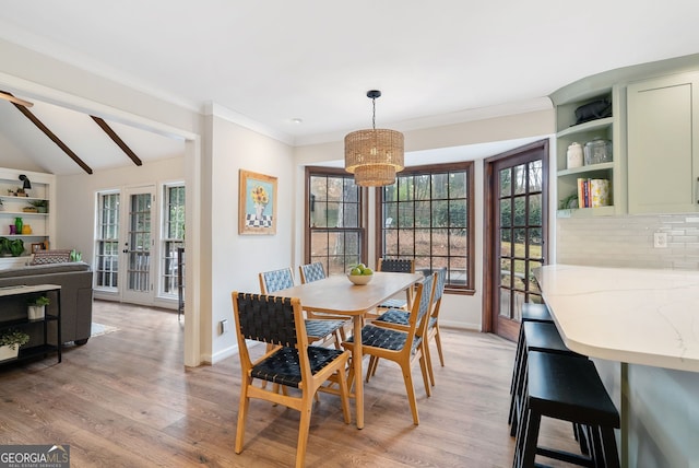 dining space with crown molding, vaulted ceiling, and light hardwood / wood-style floors