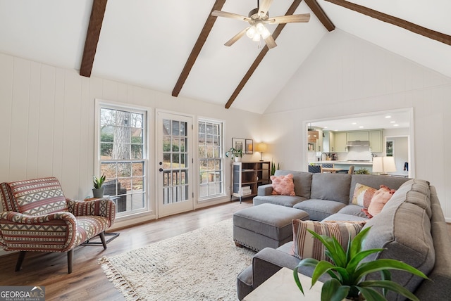 living room with ceiling fan, high vaulted ceiling, hardwood / wood-style floors, and beam ceiling