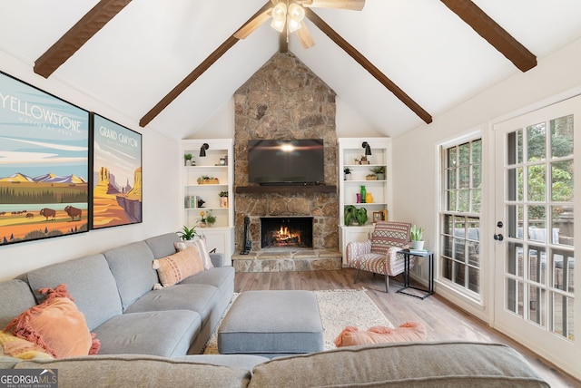 living room with a stone fireplace, hardwood / wood-style floors, high vaulted ceiling, beamed ceiling, and ceiling fan