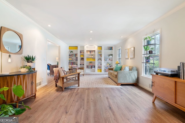 living room featuring built in shelves, ornamental molding, and light wood-type flooring