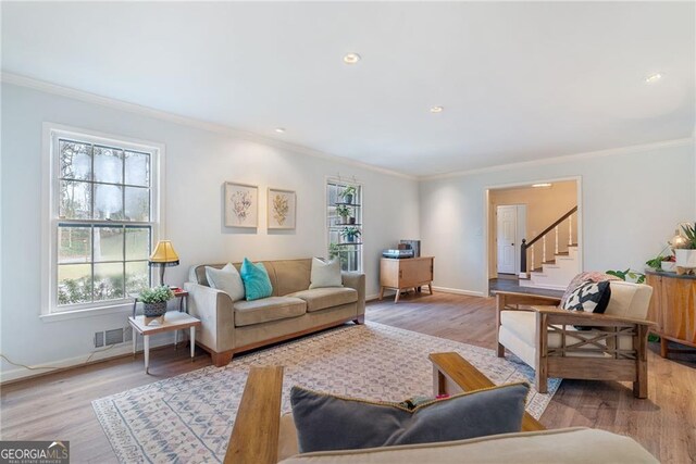 living room featuring crown molding, a wealth of natural light, and light hardwood / wood-style floors