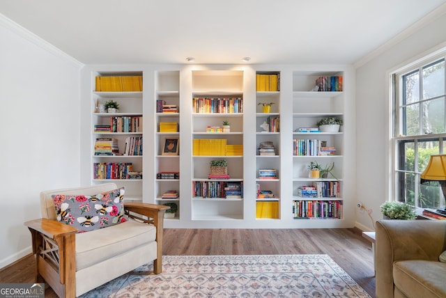 sitting room with hardwood / wood-style floors, crown molding, and built in shelves