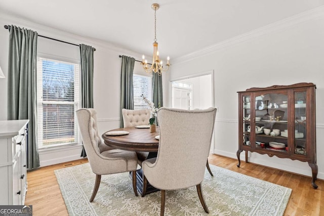 dining room featuring an inviting chandelier, light hardwood / wood-style flooring, and ornamental molding