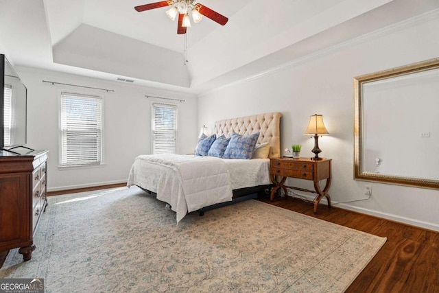 bedroom featuring a raised ceiling, ceiling fan, and dark hardwood / wood-style flooring