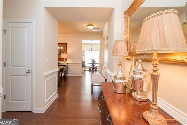 hallway featuring an inviting chandelier and dark hardwood / wood-style flooring