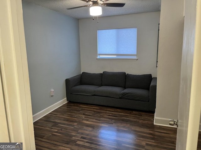 living room featuring ceiling fan, dark wood-type flooring, and a textured ceiling