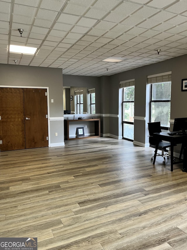 living room with a drop ceiling and light wood-type flooring