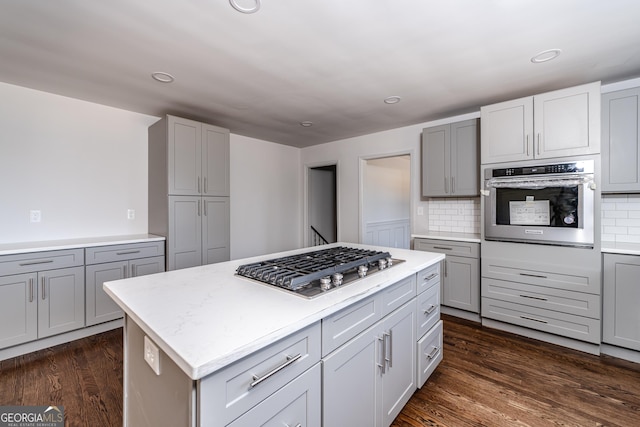 kitchen featuring tasteful backsplash, appliances with stainless steel finishes, dark hardwood / wood-style flooring, gray cabinets, and a kitchen island