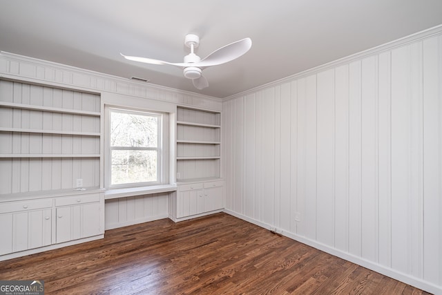 interior space featuring built in shelves, ornamental molding, dark hardwood / wood-style floors, and ceiling fan