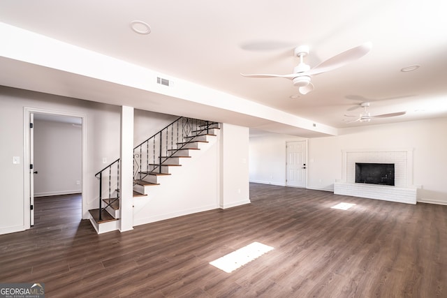 unfurnished living room featuring dark hardwood / wood-style flooring, a brick fireplace, and ceiling fan