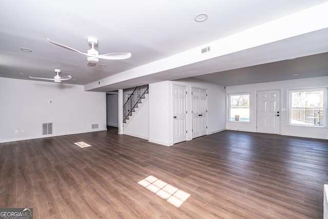 unfurnished living room featuring dark wood-type flooring and ceiling fan