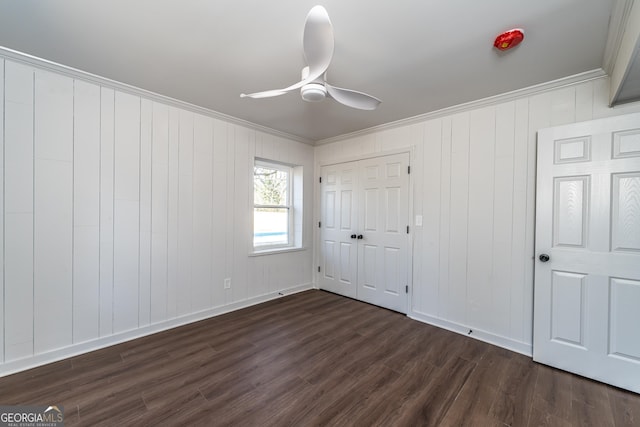 unfurnished bedroom featuring crown molding, ceiling fan, dark hardwood / wood-style floors, and a closet