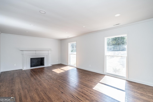 unfurnished living room featuring crown molding, plenty of natural light, and dark hardwood / wood-style flooring