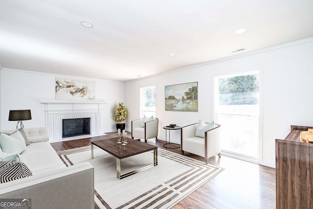 living room with crown molding, a wealth of natural light, and light hardwood / wood-style flooring