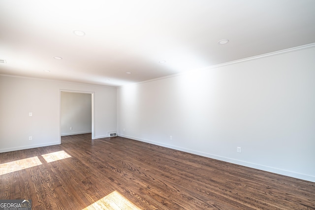 spare room with ornamental molding and dark hardwood / wood-style floors