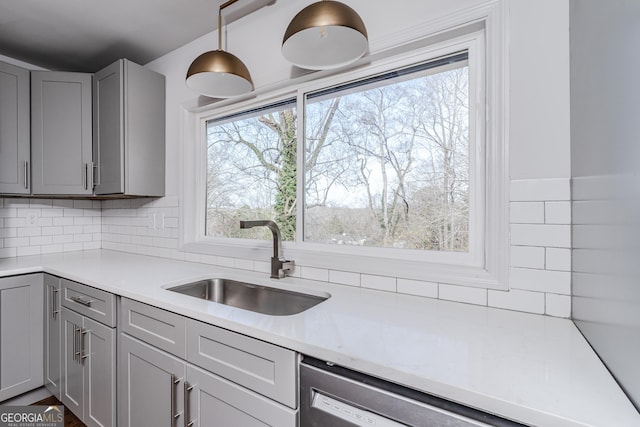 kitchen featuring pendant lighting, sink, gray cabinets, tasteful backsplash, and stainless steel dishwasher